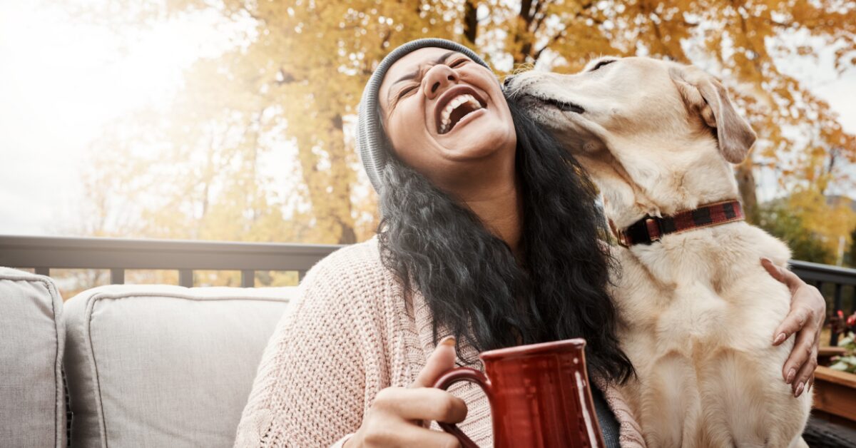 Woman smiles when a dog kisses her cheek